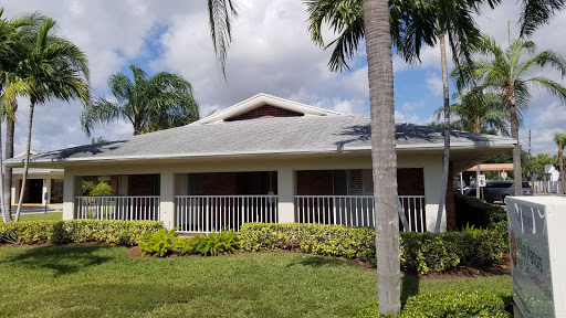 A charming residential house surrounded by palm trees and a well-maintained garden.
