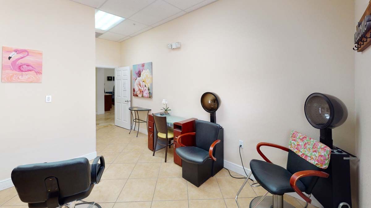 An interior view of a salon with chairs, a hair dryer, and wall artwork.