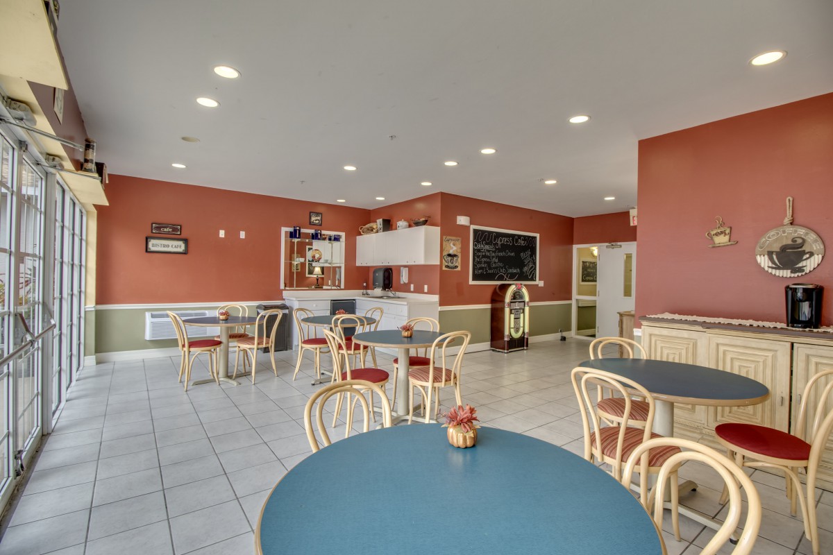A brightly lit cafe interior with several empty tables and chairs arranged neatly.