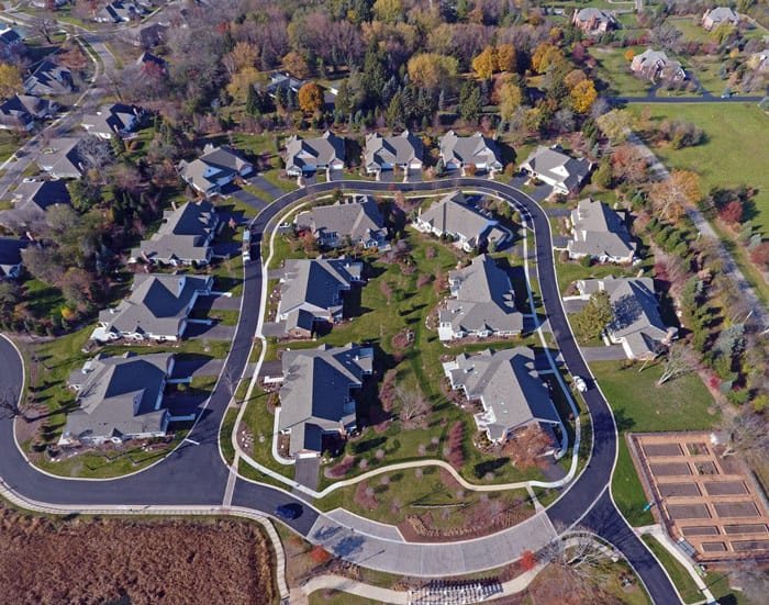 Aerial view of a suburban residential neighborhood with houses and roads surrounded by greenery.