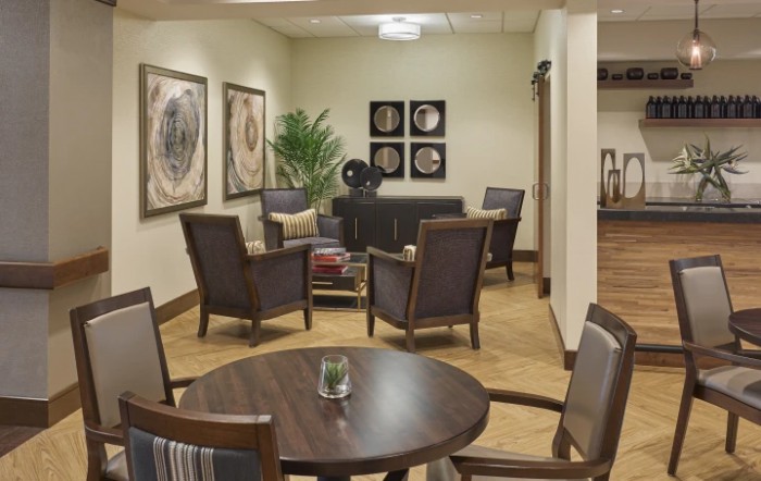 A cozy waiting room with stylish chairs, a small table, and decorative artwork on the walls.