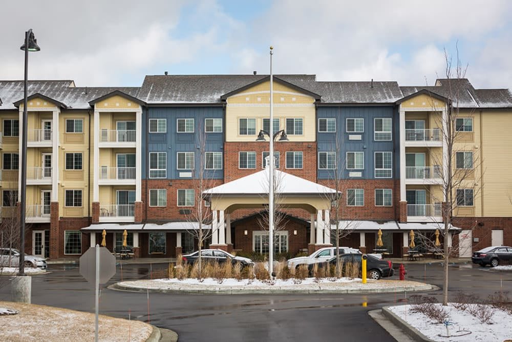 A multi-story hotel building with a covered entrance and parked cars, surrounded by snow.