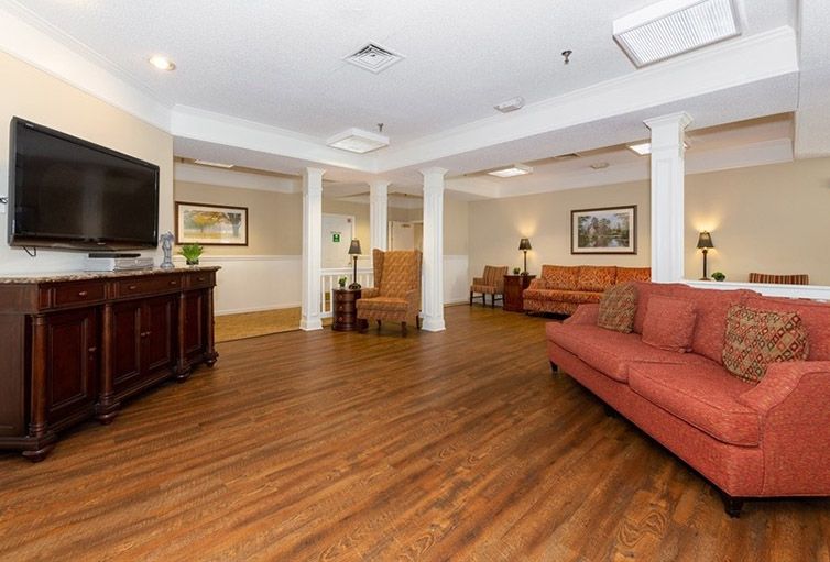 A cozy living room with wooden flooring, sofas, and ceiling lights.