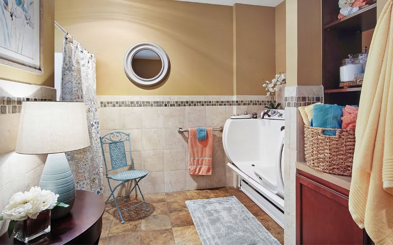 A well-organized bathroom with a bathtub, chair, and decorative elements.