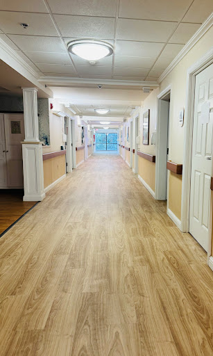 A well-lit corridor featuring wooden flooring and multiple doors leading to different rooms.