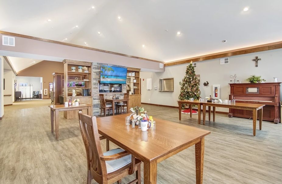 A cozy dining area with wooden tables and chairs, decorated for the holidays with a Christmas tree and festive ornaments.