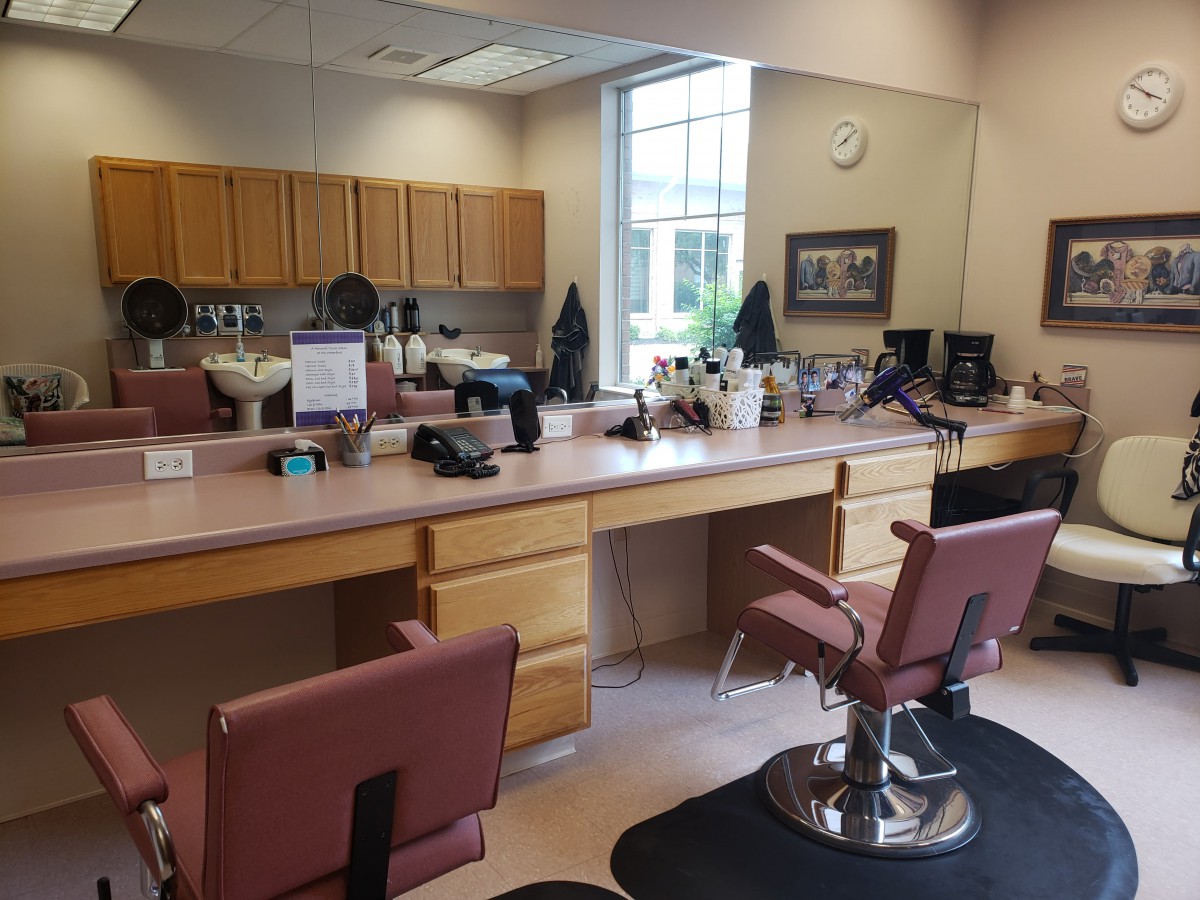 An empty barbershop with chairs and mirrors along a counter.