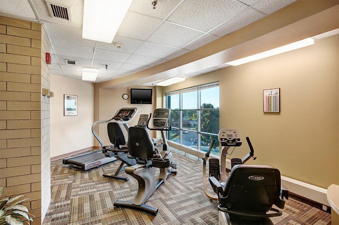 A modern gym with various fitness equipment and large windows.