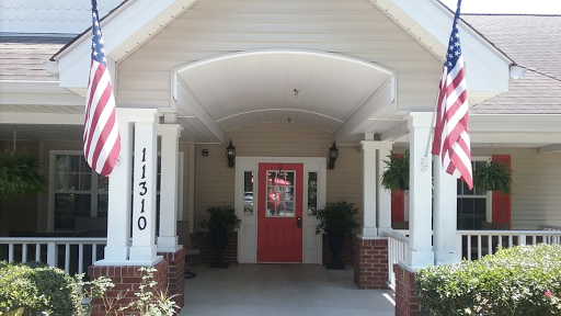 A charming home entrance featuring a vibrant red door and welcoming porch.