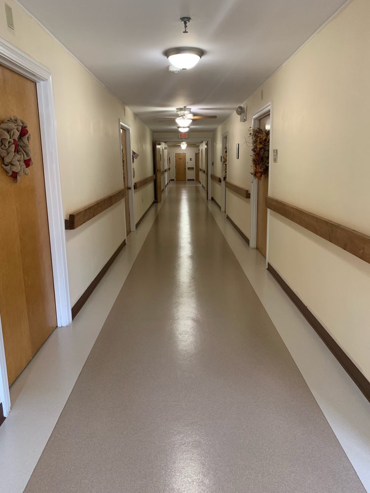 A long, empty corridor with multiple doors and bright overhead lighting.