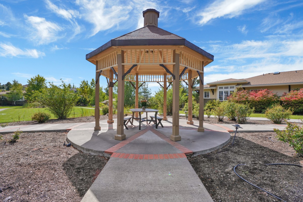 A picturesque gazebo surrounded by a garden under a clear blue sky.