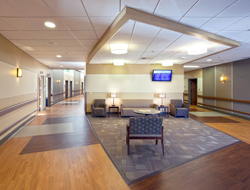 A modern hospital waiting area with comfortable seating and a television.