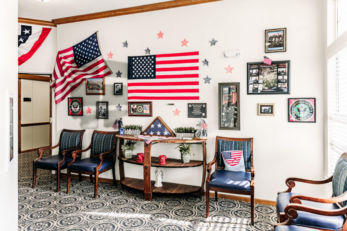 A living room adorned with American flags and military-themed decor, featuring framed photos and memorabilia on the walls.