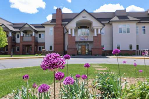A beautiful residential building surrounded by blooming flowers under a clear blue sky.