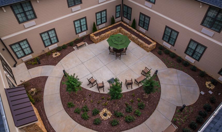 Aerial view of a landscaped courtyard featuring outdoor seating with chairs and an umbrella.