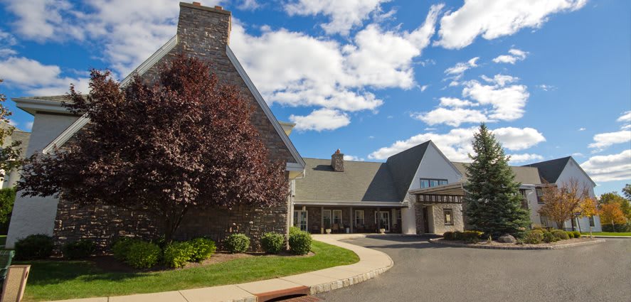 A scenic view of a building with a stone facade and pointed roof under a partly cloudy sky.