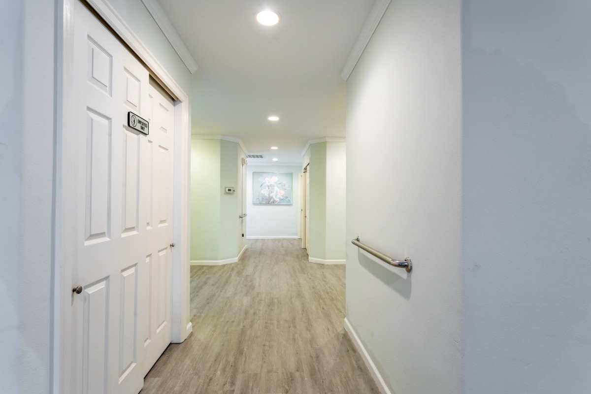 A well-lit hallway with wooden flooring and a door on the side.