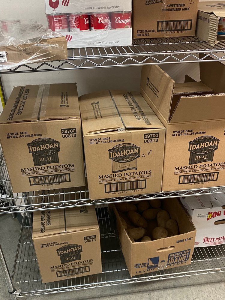 Boxes of food products organized on metal shelves in a storage area.