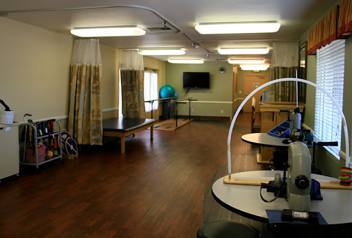 A spacious rehabilitation therapy room featuring equipment and natural light.