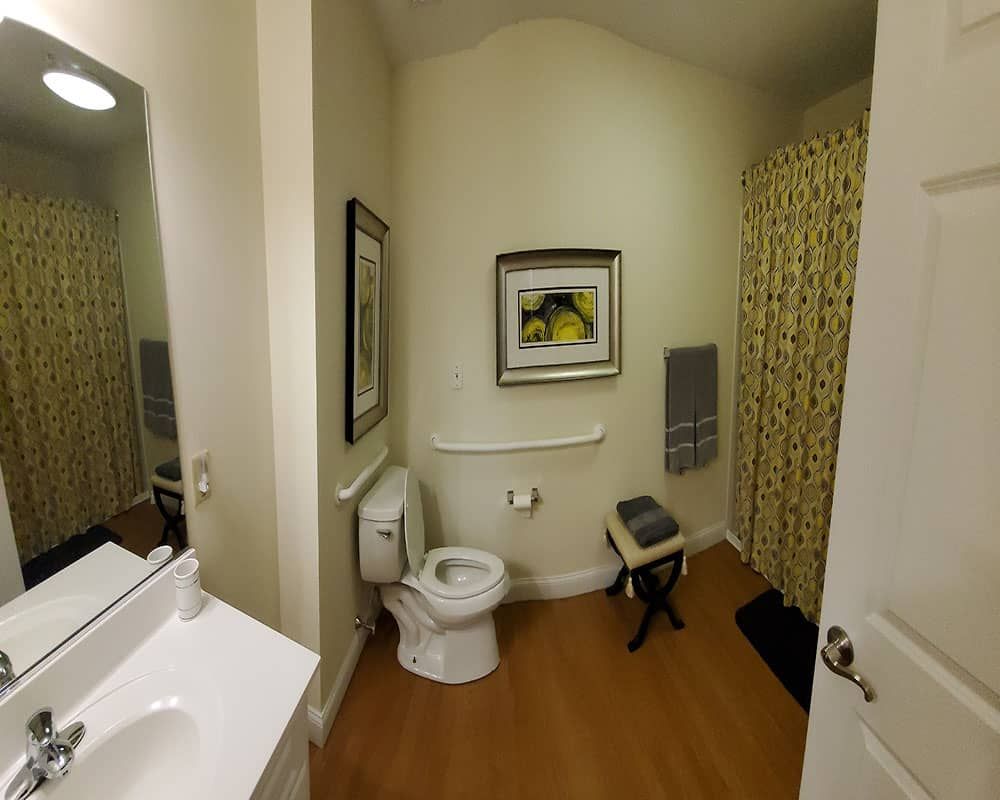 A well-organized bathroom featuring a toilet, sink, mirror, and shower area with a decorative curtain.