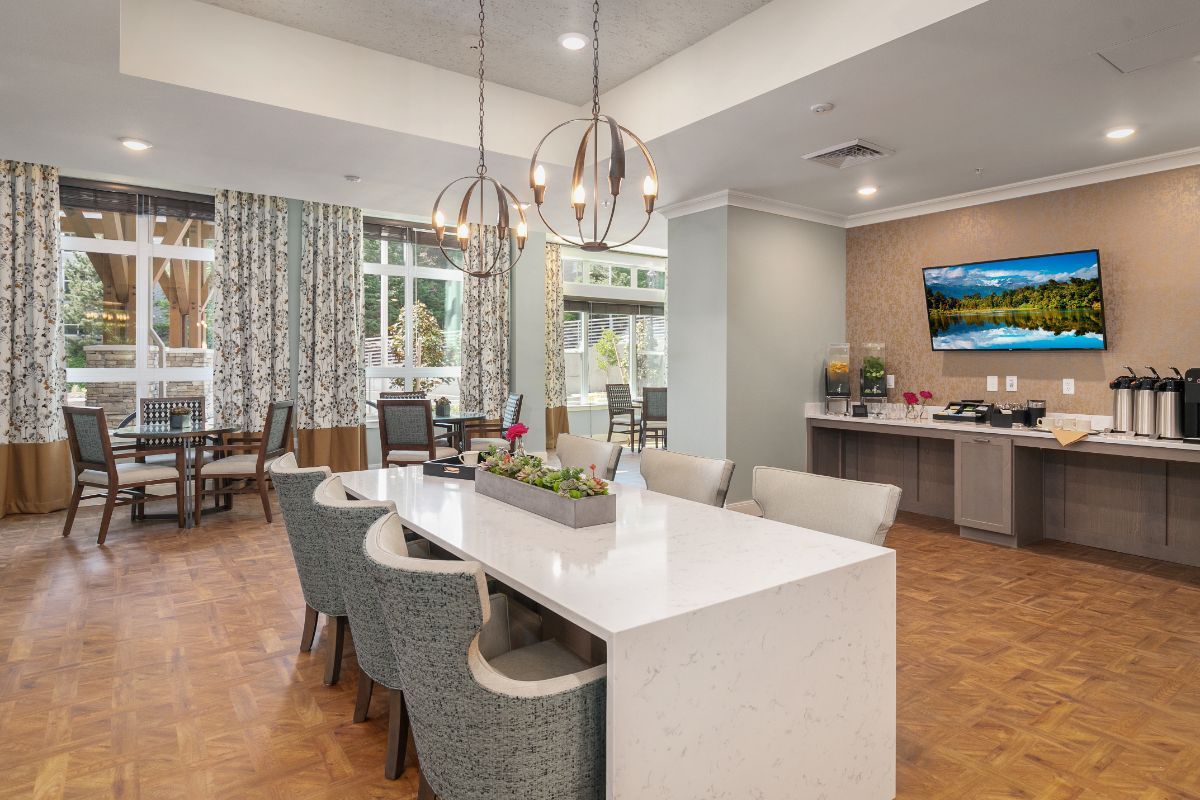 A modern dining area with a large table and comfortable chairs, featuring stylish pendant lighting and contemporary decor.