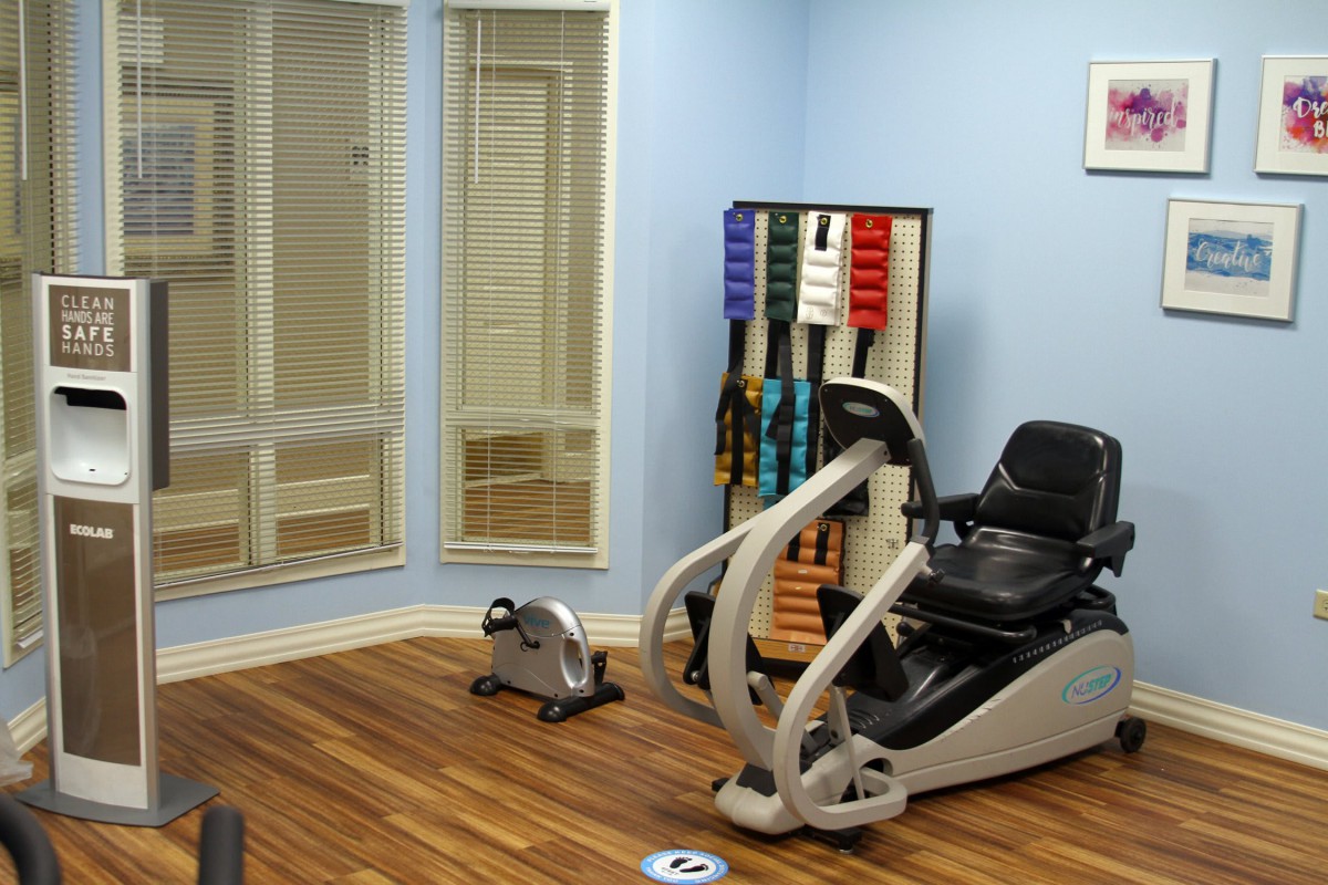 A small gym room with exercise equipment, mirrors, and karate belts on display.