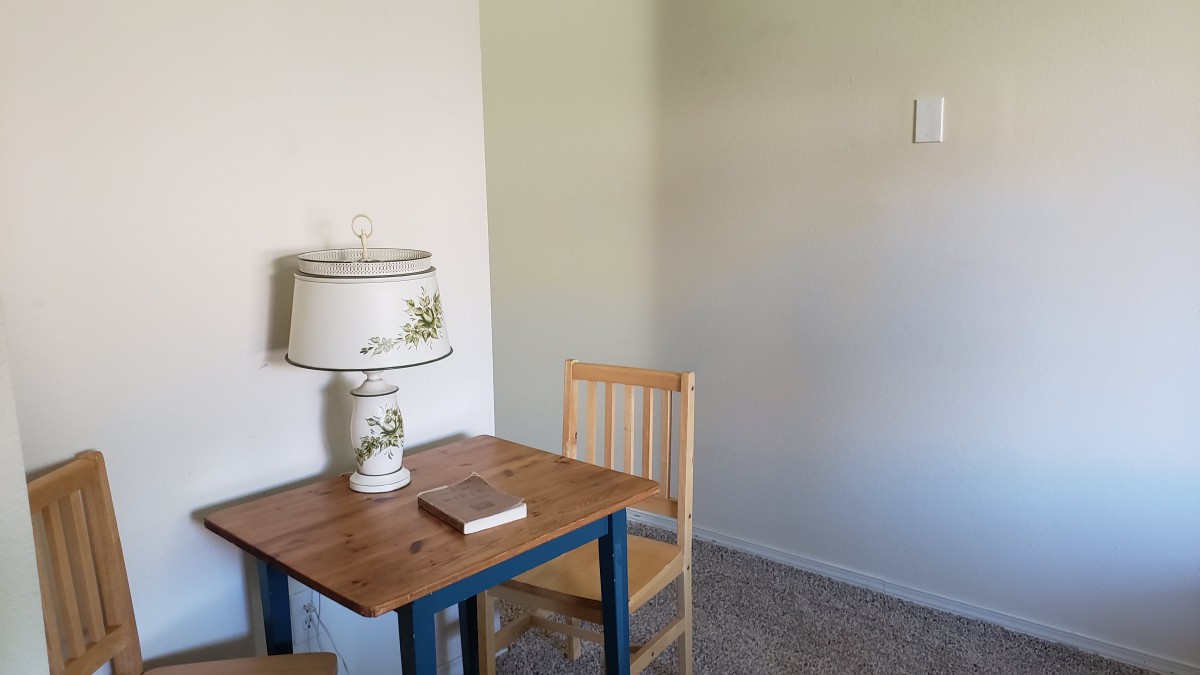 A simple room with a wooden table, chair, and a decorative lamp.