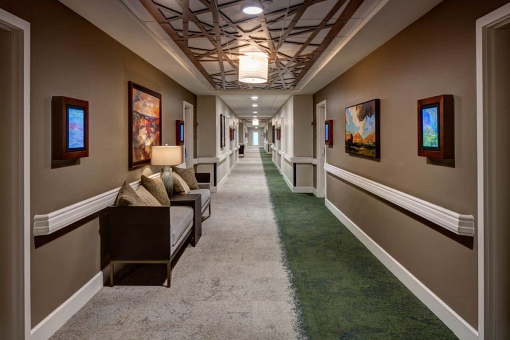 A well-decorated hotel hallway with art pieces and seating area.