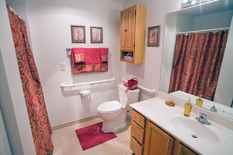 A neatly organized bathroom featuring a toilet, sink, and shower with red accents.
