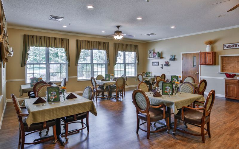 An elegant dining room with neatly arranged tables and chairs, featuring large windows and tasteful decor.