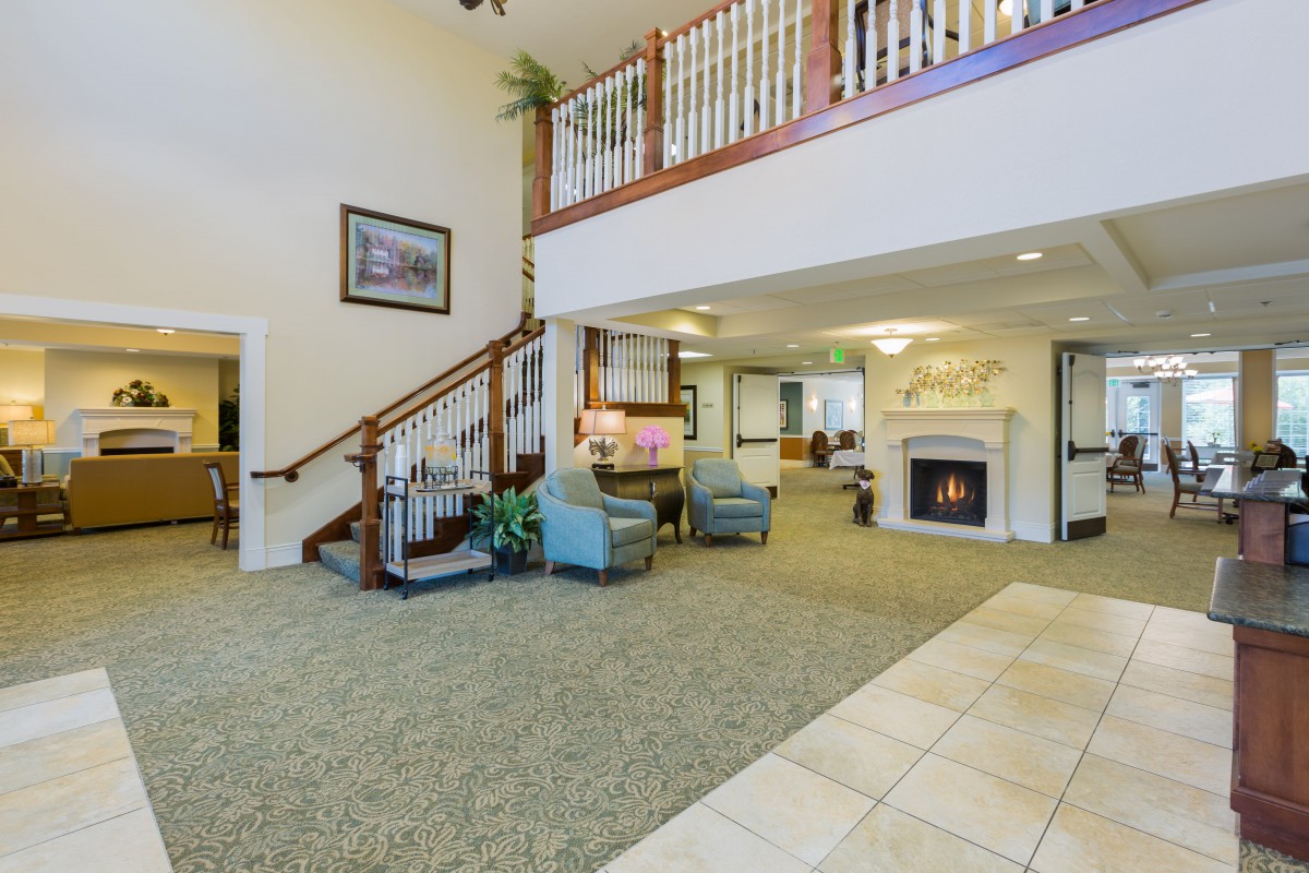 Spacious lobby with a cozy seating area, fireplace, and staircase.