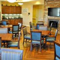 A cozy dining area with wooden tables and chairs, a fireplace, and a mounted television.