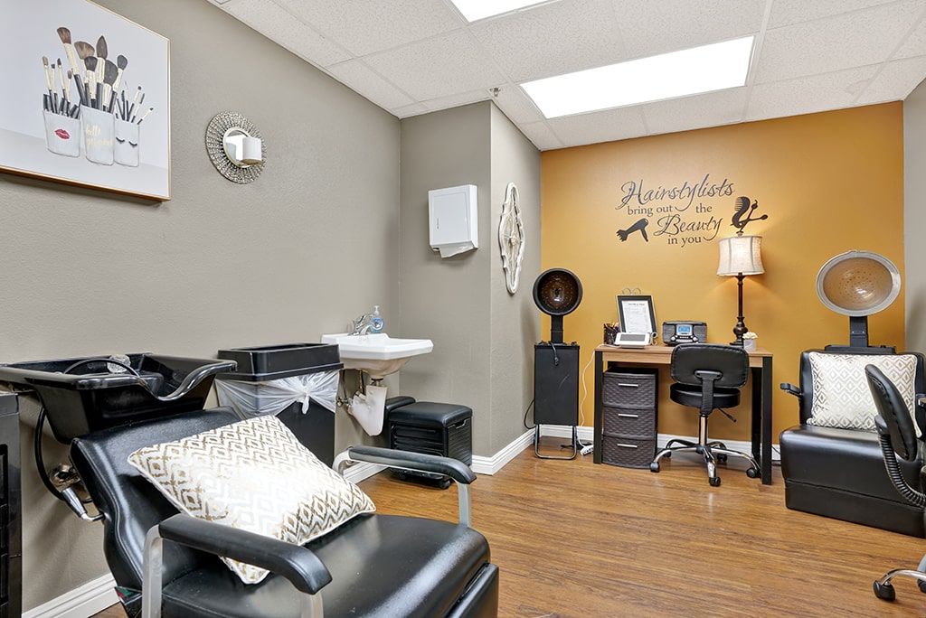 A well-organized salon interior with a comfortable seating area, work desk, and hair styling equipment.