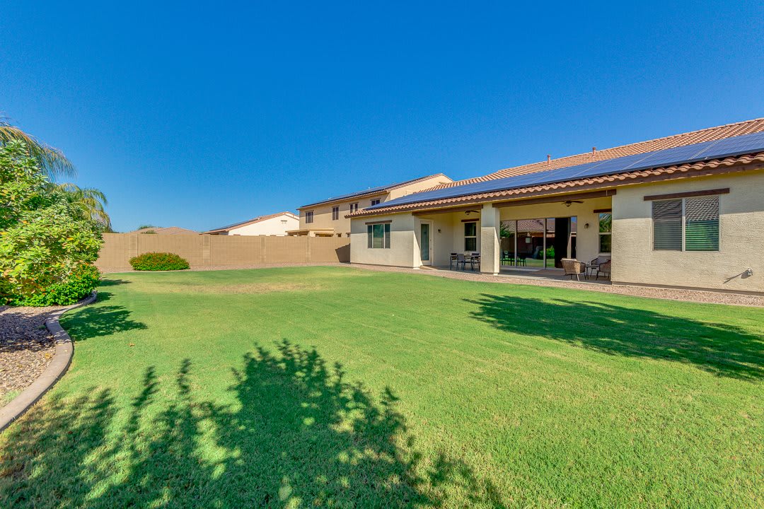 A spacious backyard with a green lawn and a patio on a sunny day.