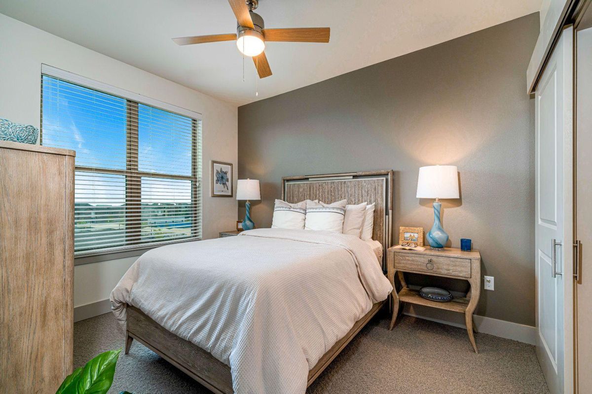 A modern bedroom featuring a comfortable bed, stylish lamps, and a large window with a scenic view.