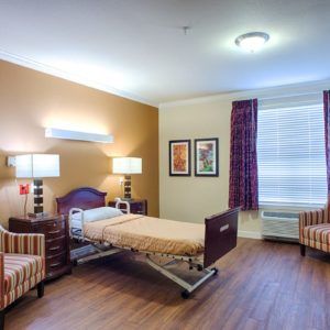 A well-lit hospital room featuring a patient bed and seating area.