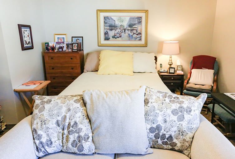 A cozy bedroom with a neatly made bed, decorative pillows, and a lamp on the nightstand.