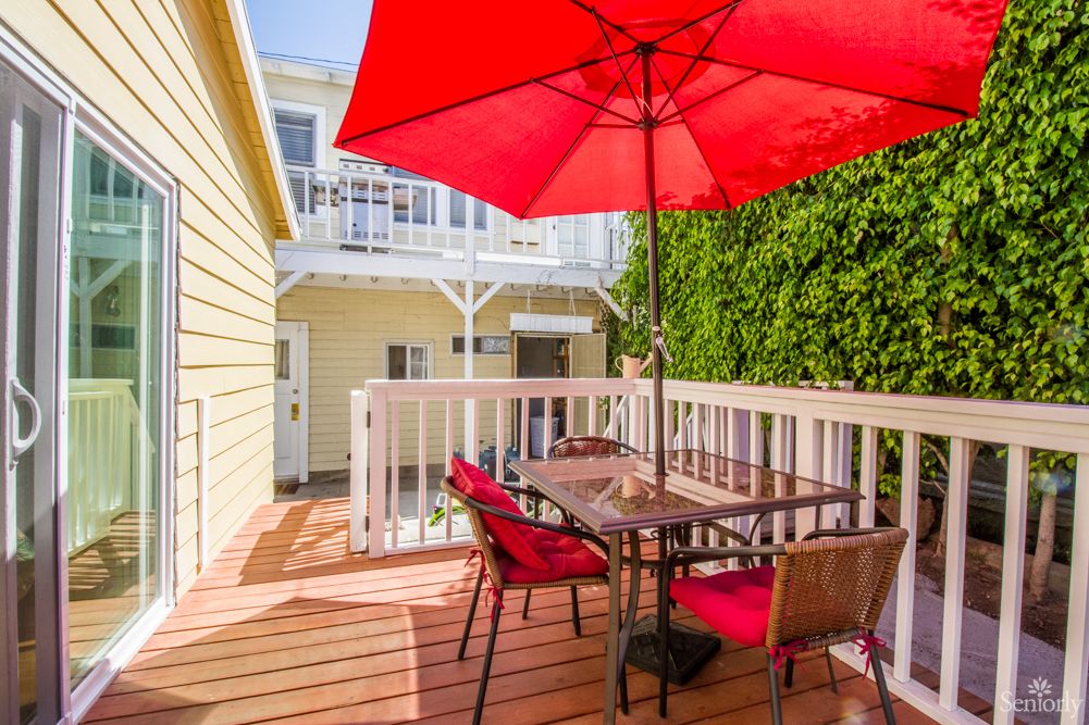 A cozy outdoor patio with a red umbrella and seating area.
