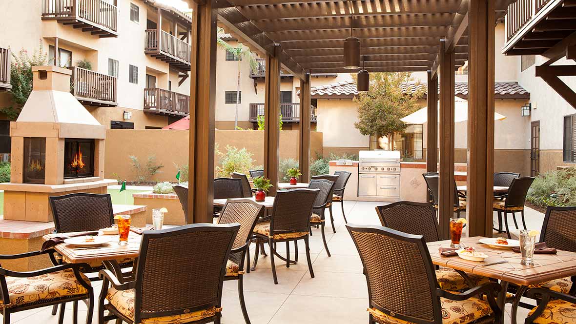 A cozy outdoor patio with tables and chairs under a pergola, ideal for relaxation.
