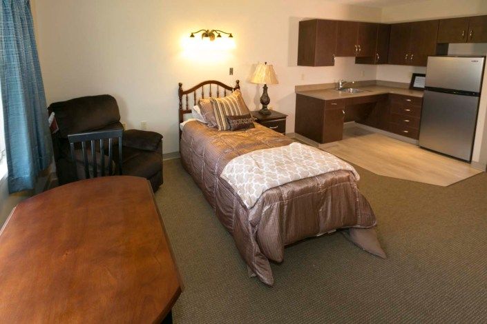 A cozy room with a single bed and kitchenette area.
