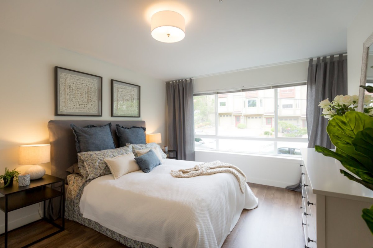 A modern and cozy bedroom with ample natural light, featuring stylish decor and comfortable furnishings.