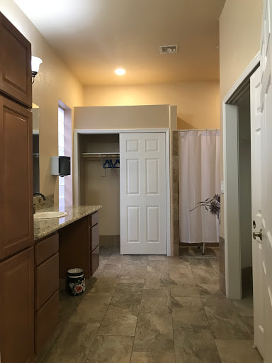 A spacious bathroom featuring a sink area, shower, and storage options.