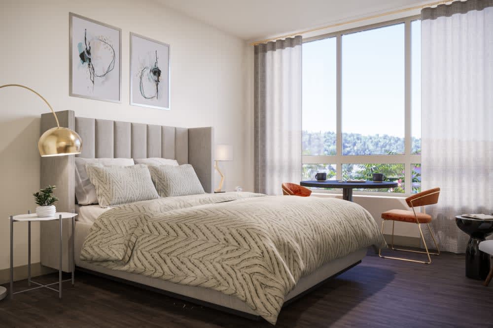 A modern bedroom with a large bed, stylish artwork, and a window offering scenic views.