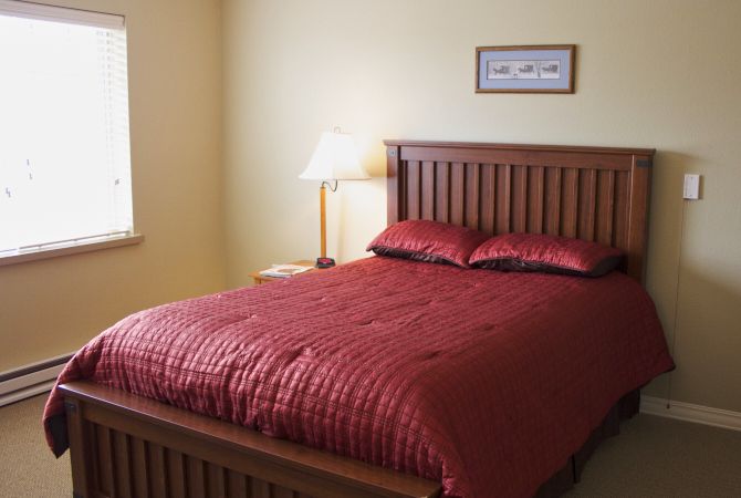 A cozy bedroom with a wooden bed and red bedding.