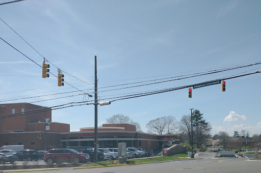 A view of a busy intersection with traffic lights and nearby buildings under a clear sky.