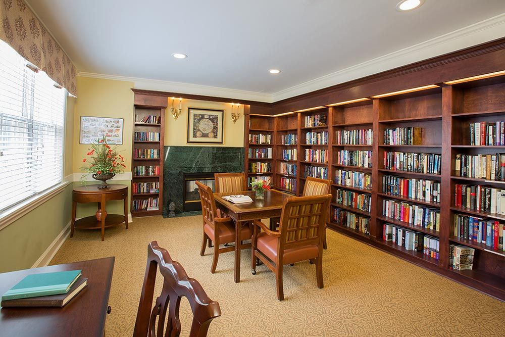A cozy library room with wooden bookshelves and a table set for reading.