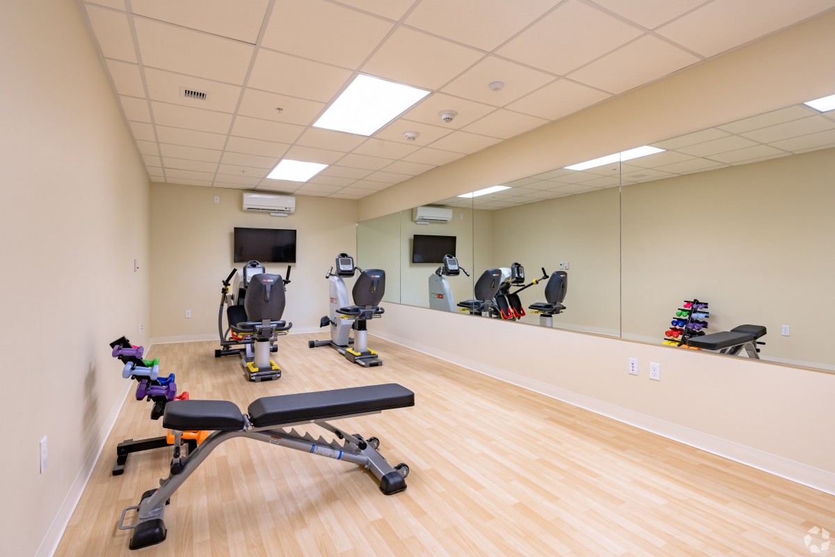 A well-equipped gym room with fitness machines and a large mirror.