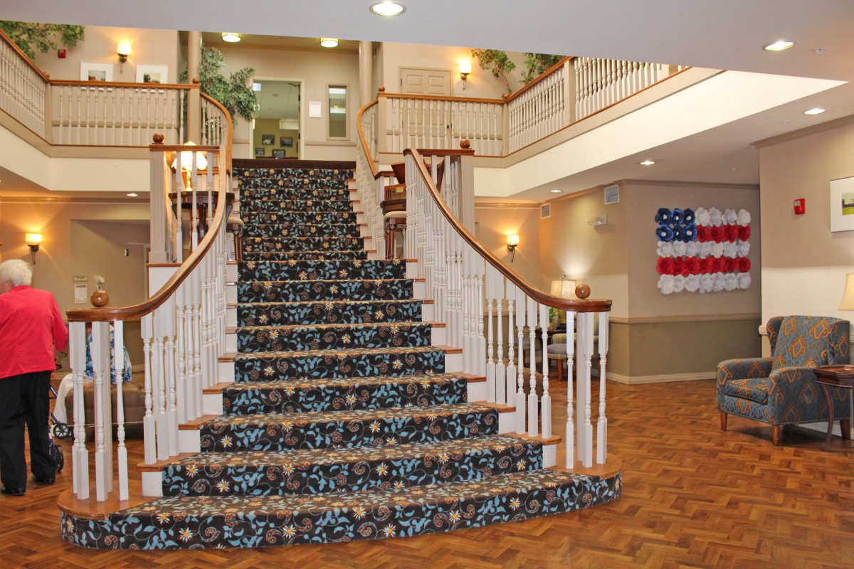 Elegant staircase in a warmly decorated lobby with an American flag on display.