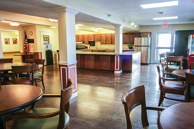 A modern kitchen and dining area with wooden cabinets, tables, and chairs in an open space.