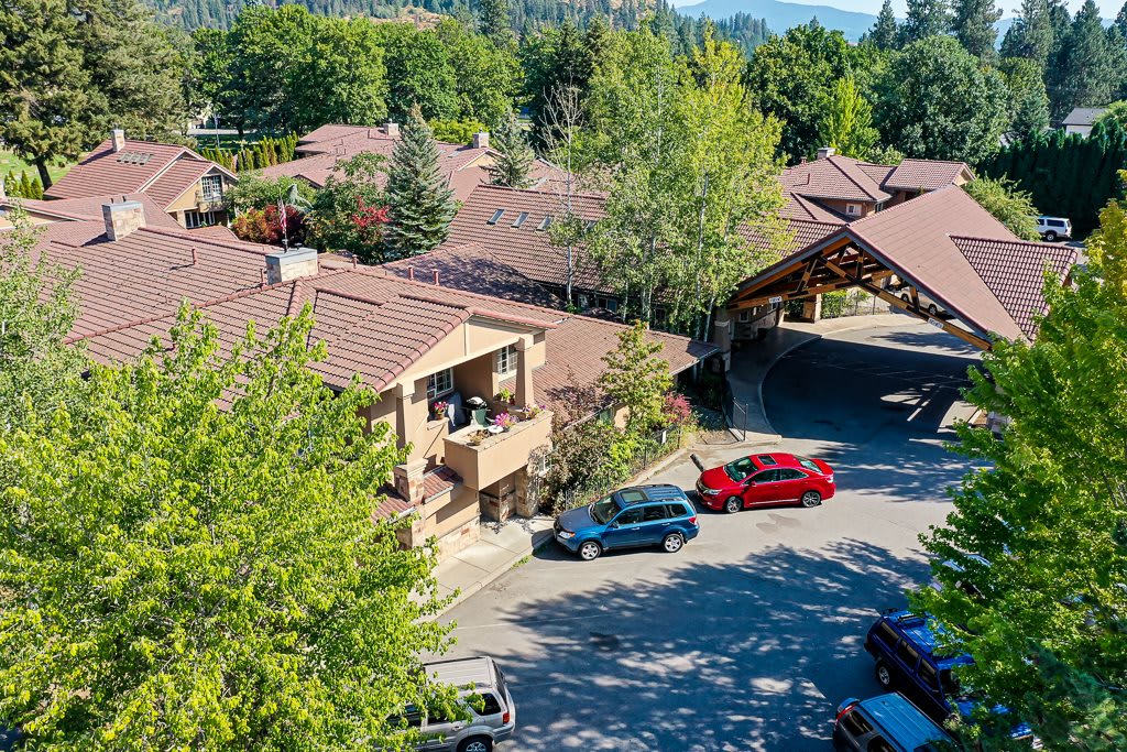 A scenic view of buildings surrounded by trees, with cars parked in a lot.